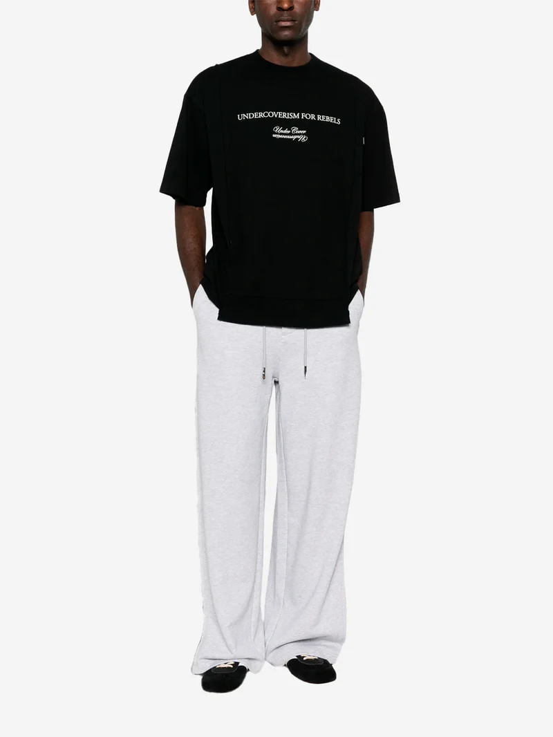 T-shirt nera con grafica 'Undercoverism' e inserti