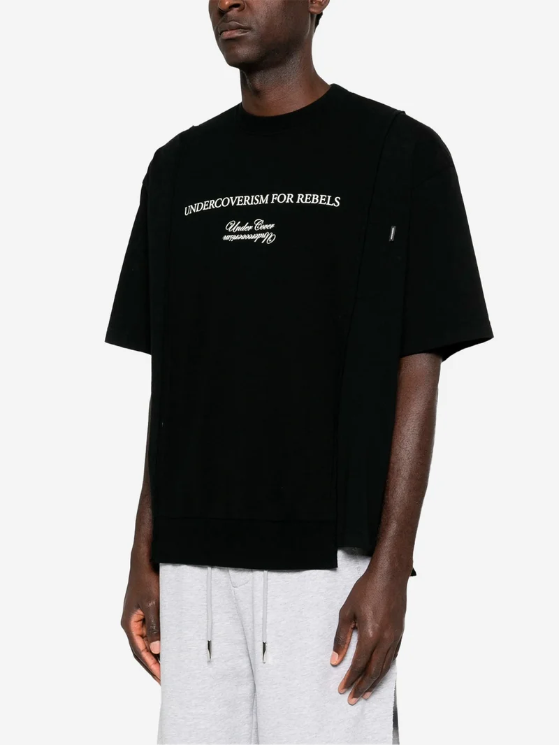 T-shirt nera con grafica 'Undercoverism' e inserti